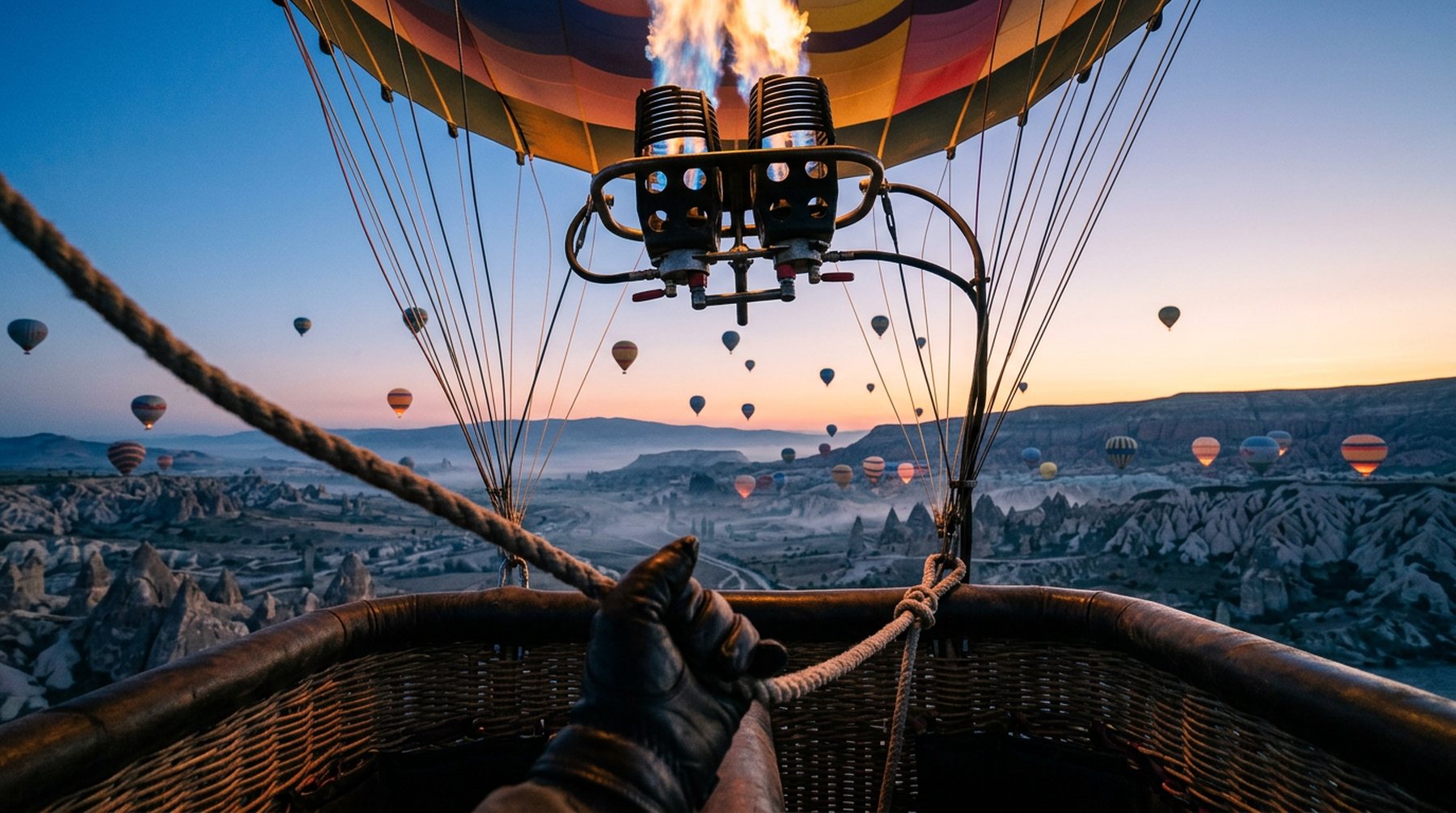 Depuis l’intérieur de la nacelle : le brûleur allumé au-dessus, la vallée de Göreme et des dizaines de montgolfières au lever du jour.